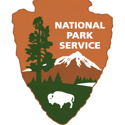 National Park Service emblem featuring a tree, mountain, buffalo, and the text "National Park Service" in a shield shape.