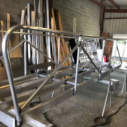 A metal frame structure inside a workshop, surrounded by various tools and wooden boards.